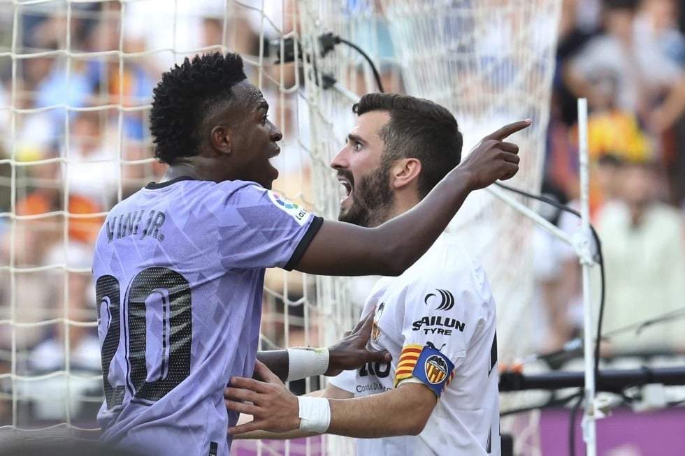 Vinicius Junior, del Real Madrid, a la izquierda, confronta a los aficionados del Valencia mientras José Luis Gayá, del Valencia, reacciona durante un partido de La Liga española de fútbol entre Valencia y Real Madrid, en el estadio de Mestalla en Valencia, España, el domingo 21 de mayo de 2023.