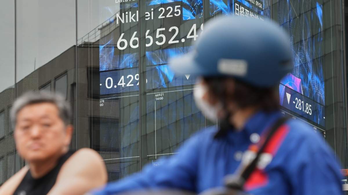 Varias personas pasan frente a una pantalla electrónica que muestra el índice Nikkei de Japón en una correduría de valores el martes 2 de junio de 2026, en Tokio