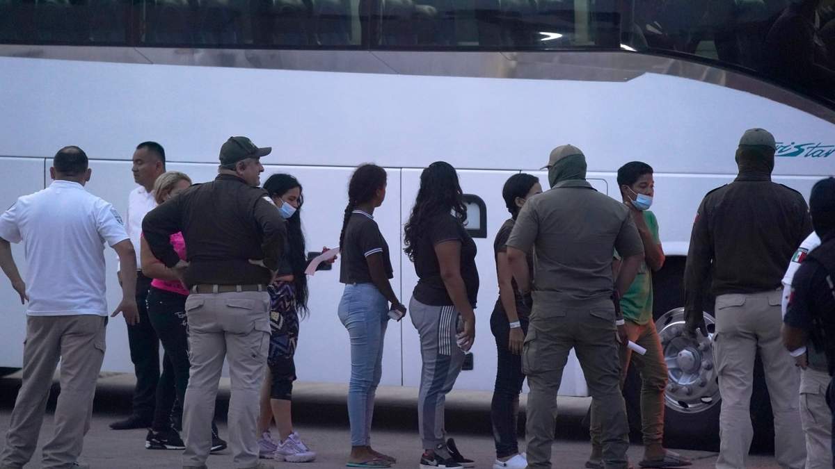 Migrantes abordan un autobús para ser deportados hacia Matamoros