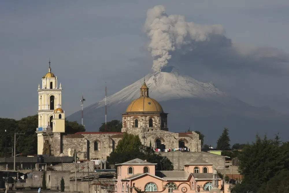 La iglesia principal de San Damián Texoloc, México, al frente del volcán Popocatépetl mientras expulsa cenizas y vapor a inicios de julio de 2013