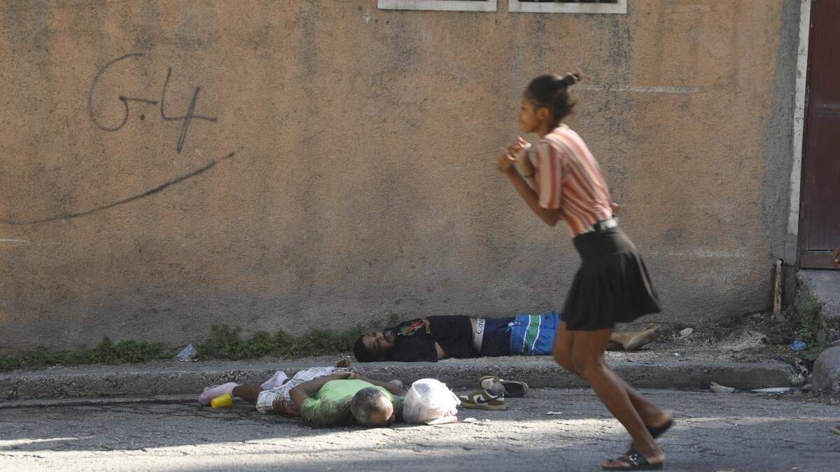 Una mujer pasa junto a los cuerpos de dos hombres asesinados por agresores desconocidos en Puerto Príncipe, Haití, el domingo 3 de marzo de 2024. Cientos de presos huyeron de la principal prisión de Haití después de que pandilleros armados asaltaran el complejo durante la noche