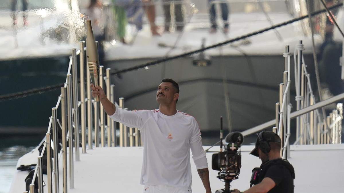 El primer portador de la antorcha olímpica en Francia, el nadador francés Florent Manaudou, sostiene la antorcha tras bajar del Belem, un barco de vela de tras mástiles en el puerto antiguo de Marsella, en el sur de Francia, el miércoles 8 de mayo de 2024. Tras salir de Marsella, una larga ruta de relevos llevará la llama olímpica por Francia hasta llegar a París el 27 de julio