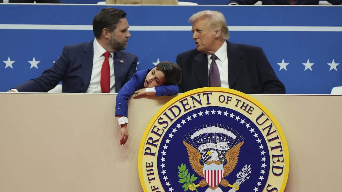El vicepresidente JD Vance, el presidente Donald Trump y el hijo de Vance, Vivek, miran un desfile bajo techo por la investidura presidencial