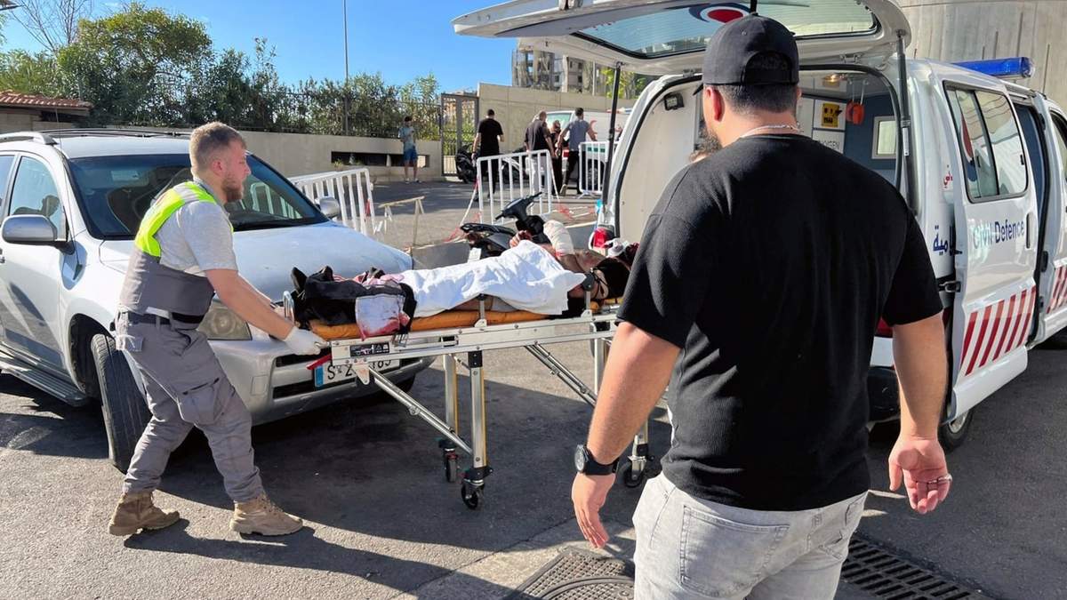 Personal de defensa civil ayuda a un hombre herido cuando estalló su buscapersonas, en Beirut, Líbano