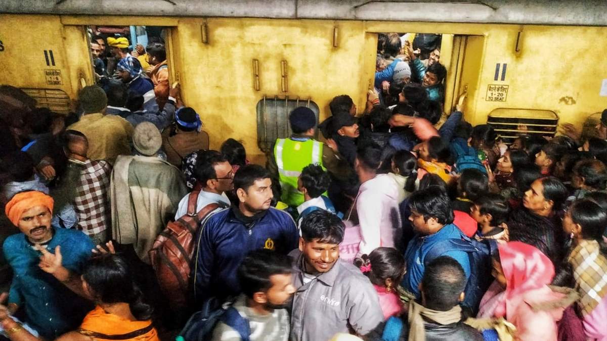 Pasajeros se empujan para abordar un tren en la estación de Nueva Delhi, India, el sábado 15 de febrero de 2025