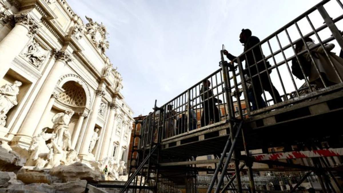 Personas caminan por una pasarela elevada que da acceso limitado a la Fuente de Trevi durante trabajos de mantenimiento en Roma