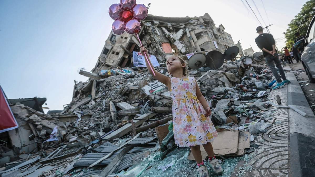 Una niña sostiene unos globos en medio de la destrucción generalizada en la Franja de Gaza. Fuente: (Twitter)