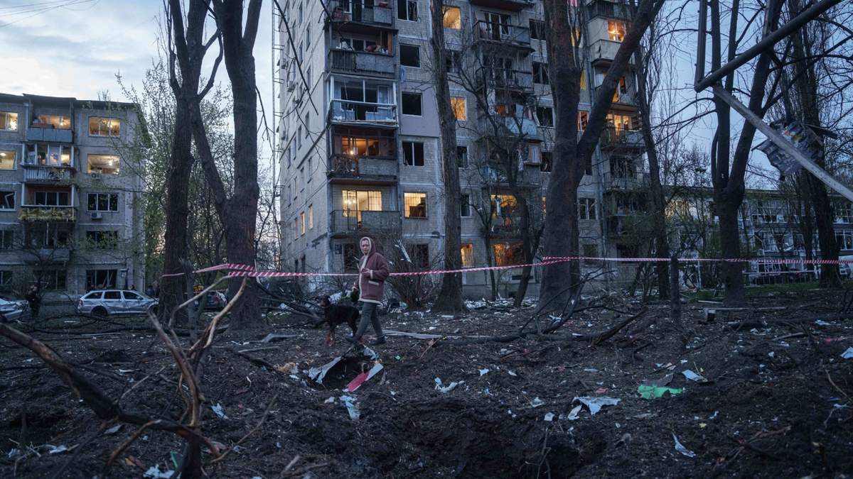 Una mujer pasea con un perro entre los escombros de una casa dañada en un ataque ruso a una zona residencial en Kiev, Ucrania, el 16 de abril de 2026