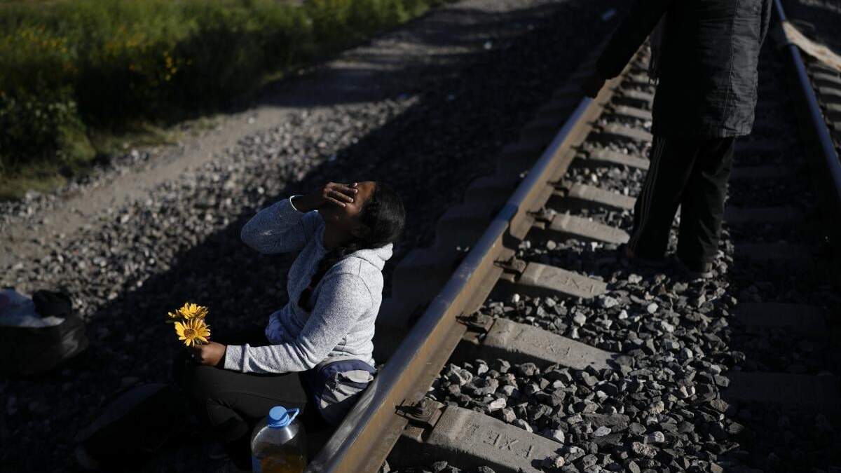 Una mujer migrante sentada al lado de las vías del tren con la esperanza de subirse a un tren de mercancías con ruta al norte en Huehuetoca, México
