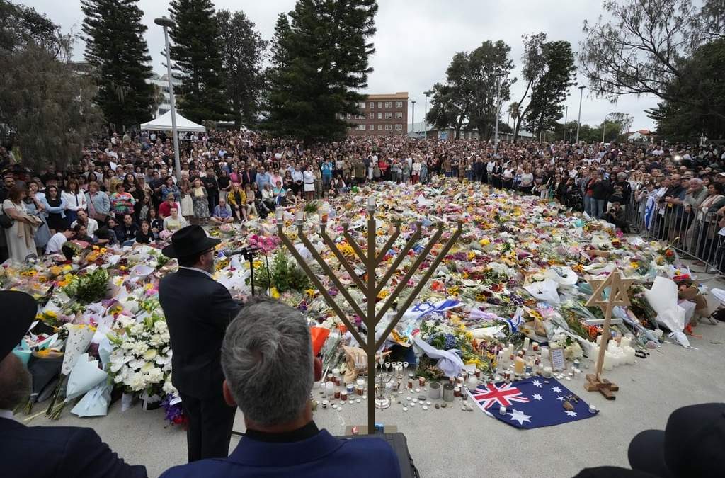 El rabino Motti Feldman, abajo a la izquierda, habla en una ceremonia de encendido de la menorá en un homenaje floral a las víctimas del tiroteo del domingo, en el Bondi Pavilion de Bondi Beach, el martes 16 de diciembre de 2025, en Sídney, Australia
