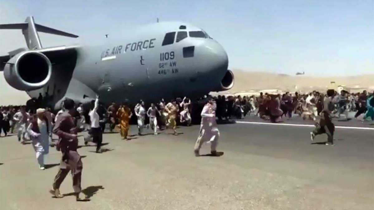 Cientos de personas corren al lado de un avión de la Fuerza Aérea de EU en la terminal de Kabul