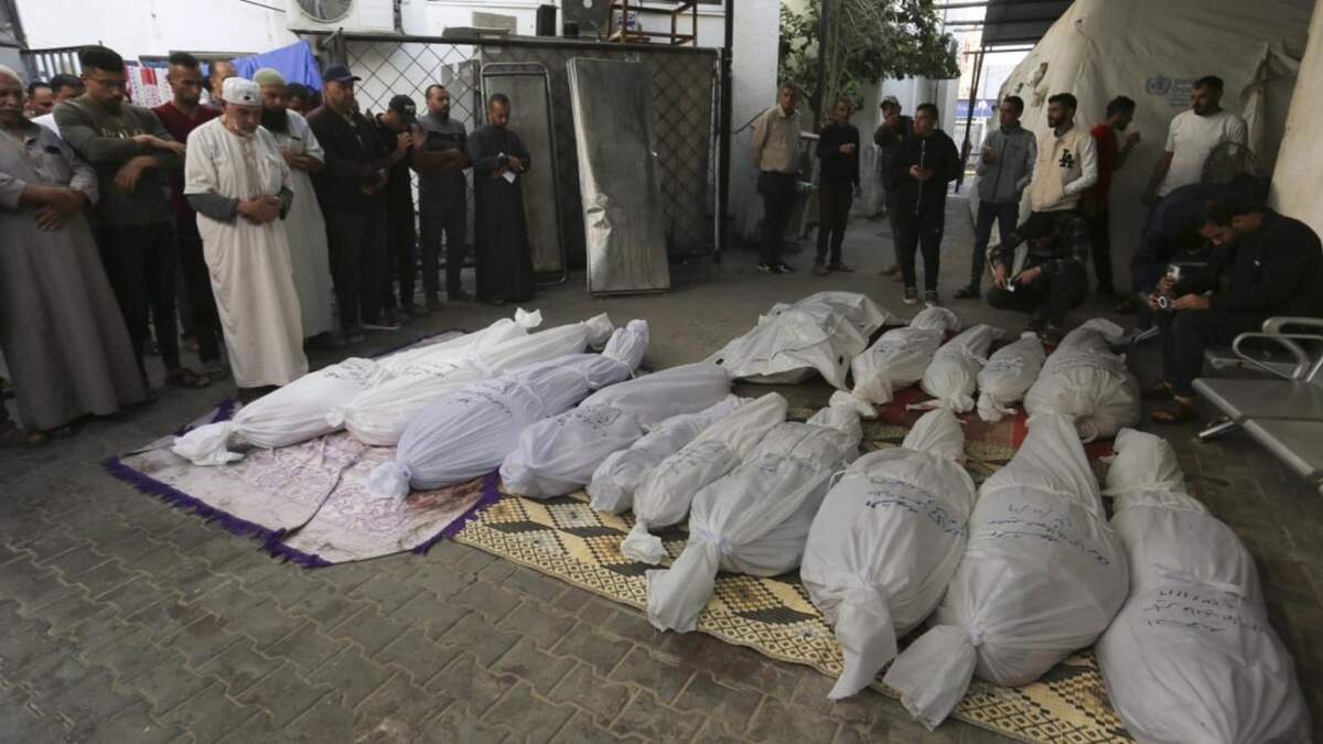 Palestinos rezan junto a los cadáveres de los miembros de la familia Hijazi que murieron en un bombardeo israelí sobre la Franja de Gaza, en Rafah
