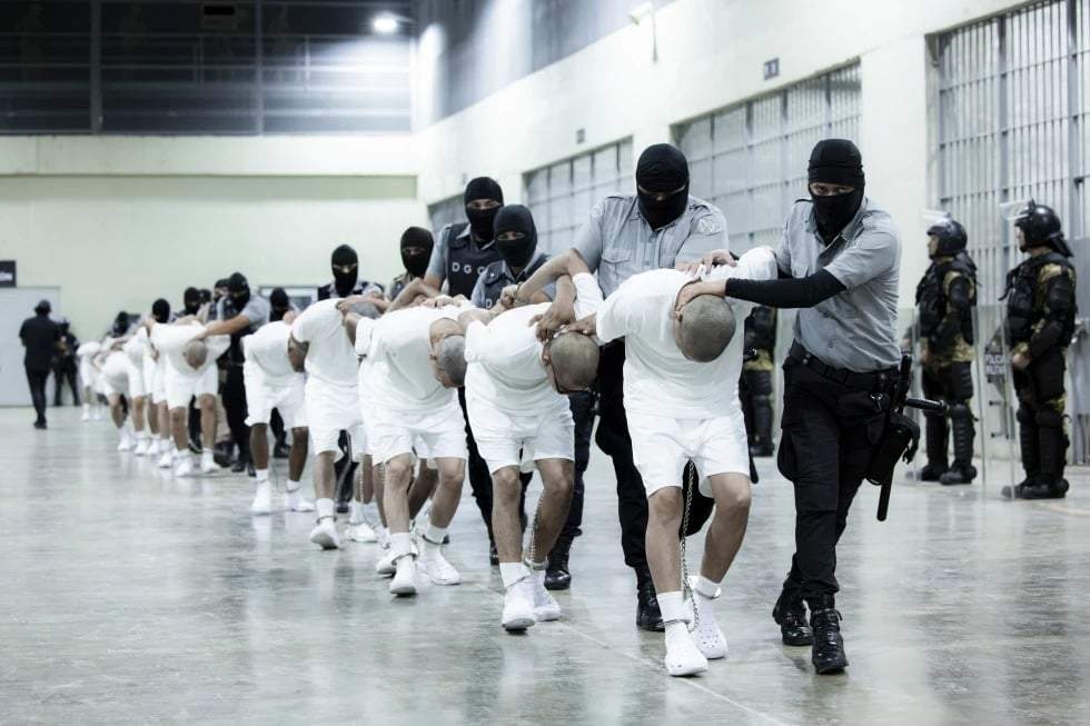 En esta fotografía proporcionada por la oficina de prensa de la presidencia de El Salvador, guardias penitenciarios trasladan a deportados de Estados Unidos, presuntos pandilleros venezolanos, al Centro de Reclusión Antiterrorista en Tecoluca, El Salvador, el domingo 16 de marzo de 2025
