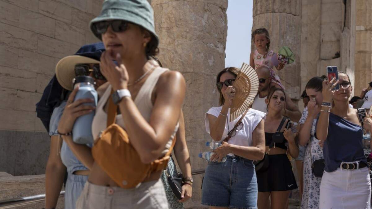 Turistas visitan la antigua colina de la Acrópolis durante una la de calor en Atenas, Grecia