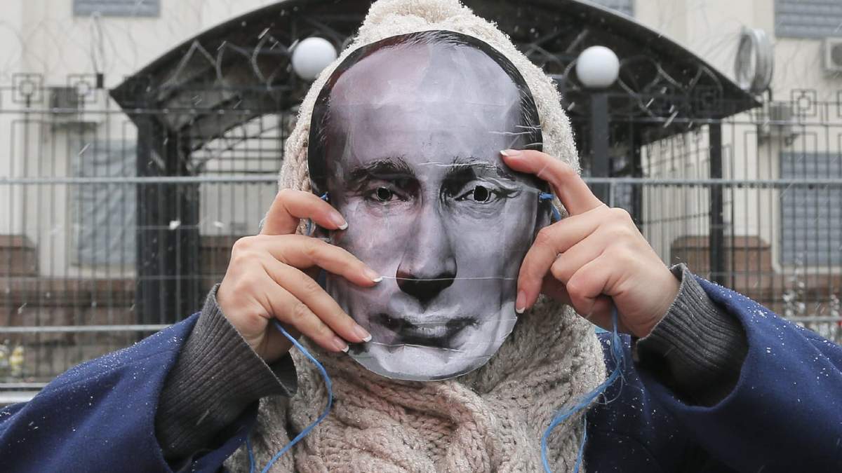 Una mujer porta una mascara con la imagen del Presidente Vladimir Putin durante una protesta afuera de la embajada Rusa en Kiev, Ucrania