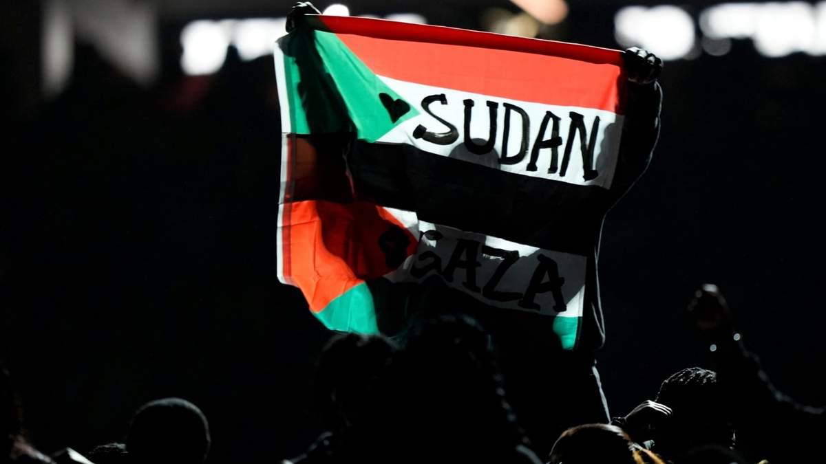 Un individuo alza una bandera que menciona a Sudán y Gaza durante el descanso del Super Bowl, el domingo 9 de febrero de 2025, en Nueva Orleans