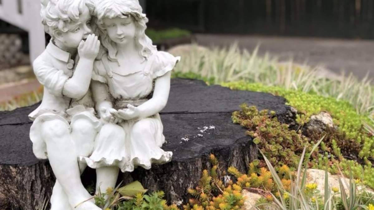 Escultura de dos niños hablando en susurros