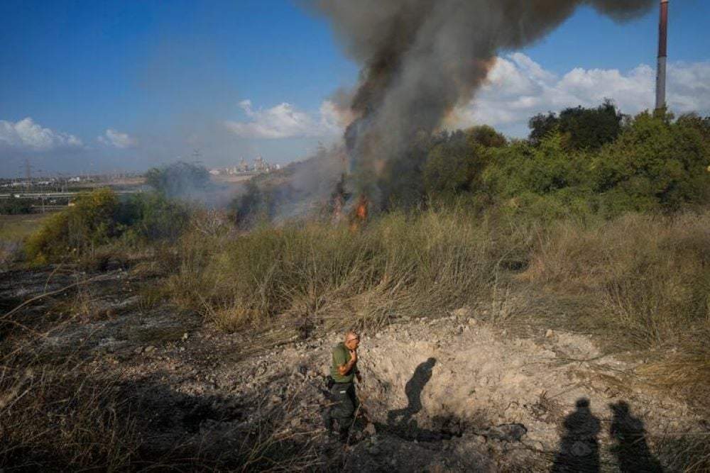 Un agente de policía inspecciona la zona en torno a un incendio después de que el ejército dijera haber lanzado proyectiles para interceptar un misil lanzado desde Yemen que aterrizó en el centro de Israel