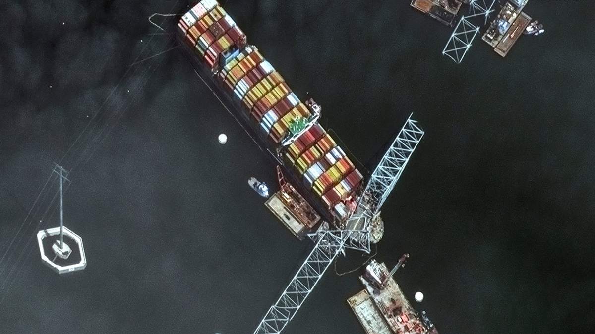 Esta imagen por satélite proporcionada por Maxar muestra la proa del barco portacontenedores Dali, bloqueado bajo tramos del puente Francis Scott Key Bridge, mientras equipos de rescate y remolcadoras siguen retirando restos del puente y cientos de contenedores aún a bordo del barco