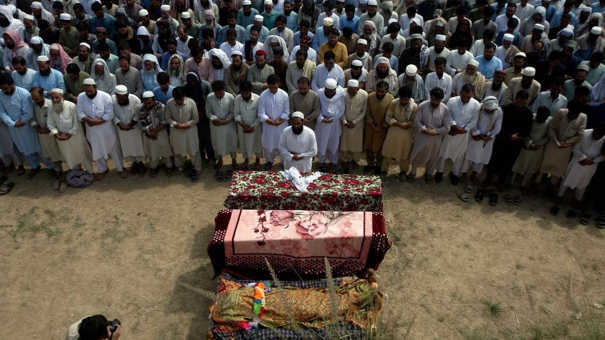 Familiares y otros dolientes oran en el funeral de víctimas de un atentado suicida en un mitin electoral