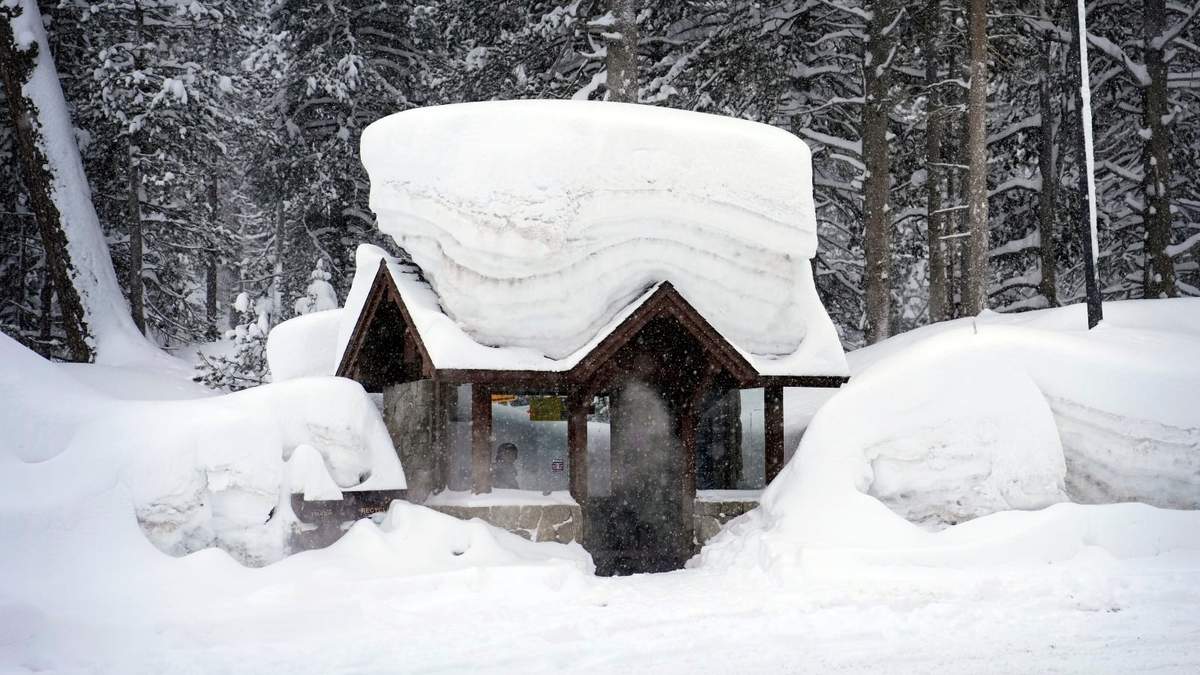 Una persona permanece en una parada de autobús cubierta por la nieve en Olympic Valley, California