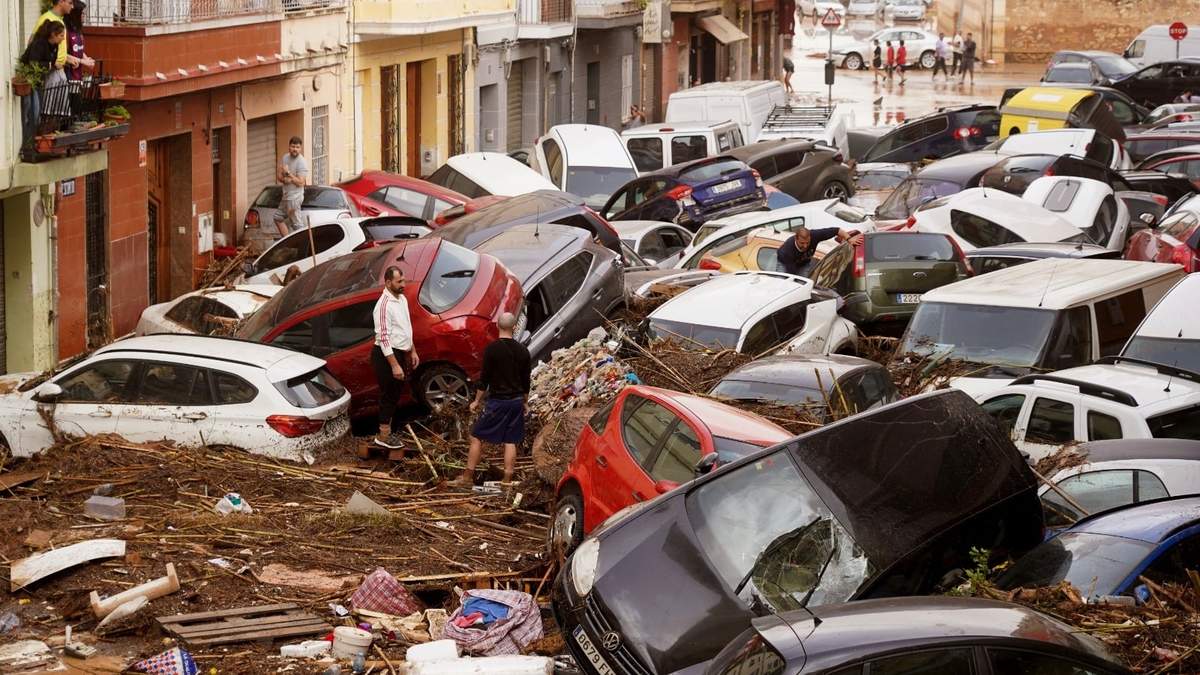 Residentes observan los autos amontonados luego de ser arrastrados por las inundaciones en Valencia, España