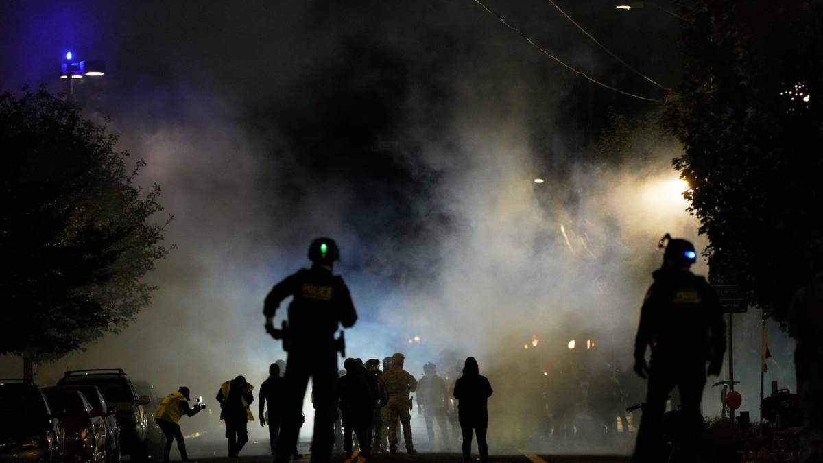 Policías montan guardia tras lanzar gases lacrimógenos afuera de unas instalaciones del Servicio de Inmigración y Control de Aduanas, el sábado 4 de octubre de 2025, en Portland, Oregon
