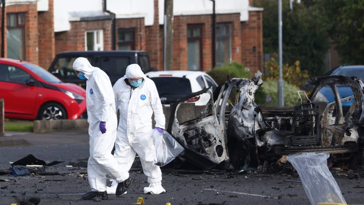Investigadores forenses inspeccionan el lugar donde estalló un auto ante la comisaría de Dunmurry , en el sur de Belfast, el domingo 26 de abril de 2026