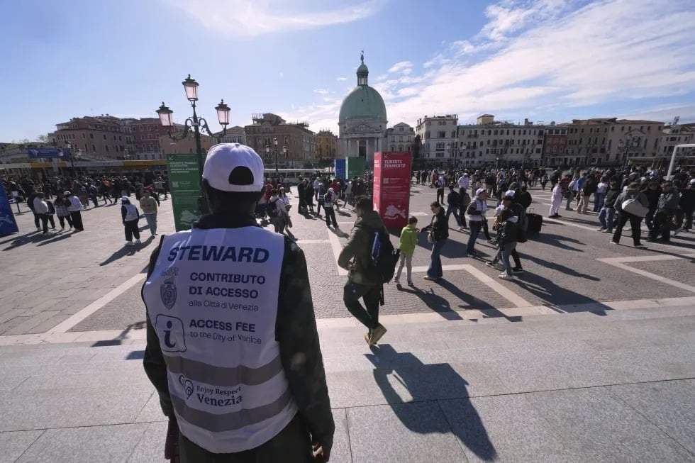 Varios empleados revisan los códigos QR de los visitantes fuera de la principal estación de trenes de Venecia, Italia, el viernes 18 de abril de 2025. La ciudad cobrará un impuesto de llegada a los viajeros de un día por segundo año consecutivo.