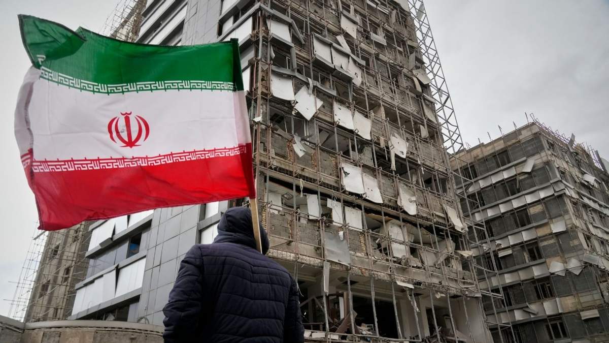Un hombre sujeta una bandera iraní tras un ataque en Teherán