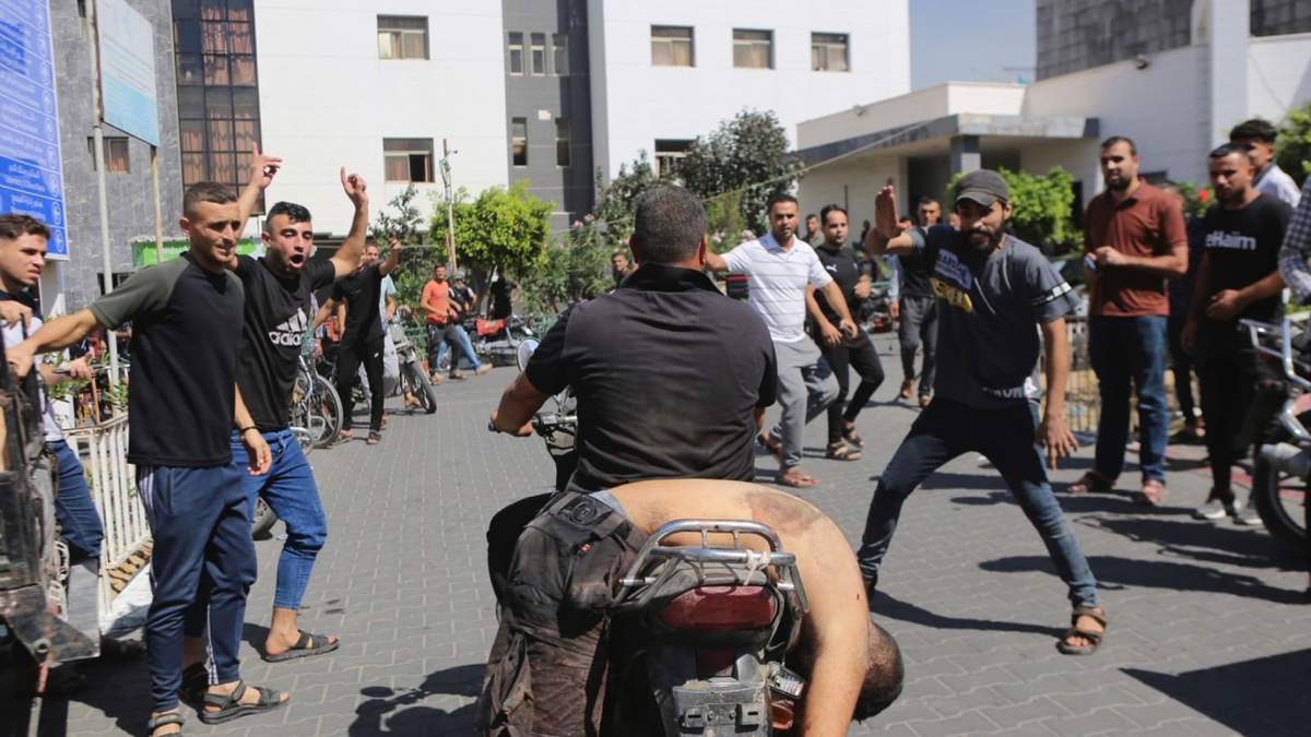 Un palestino viaja con el cuerpo de un israelí asesinado por militantes de Hamas en un kibutz cerca de la valla de la Franja de Gaza