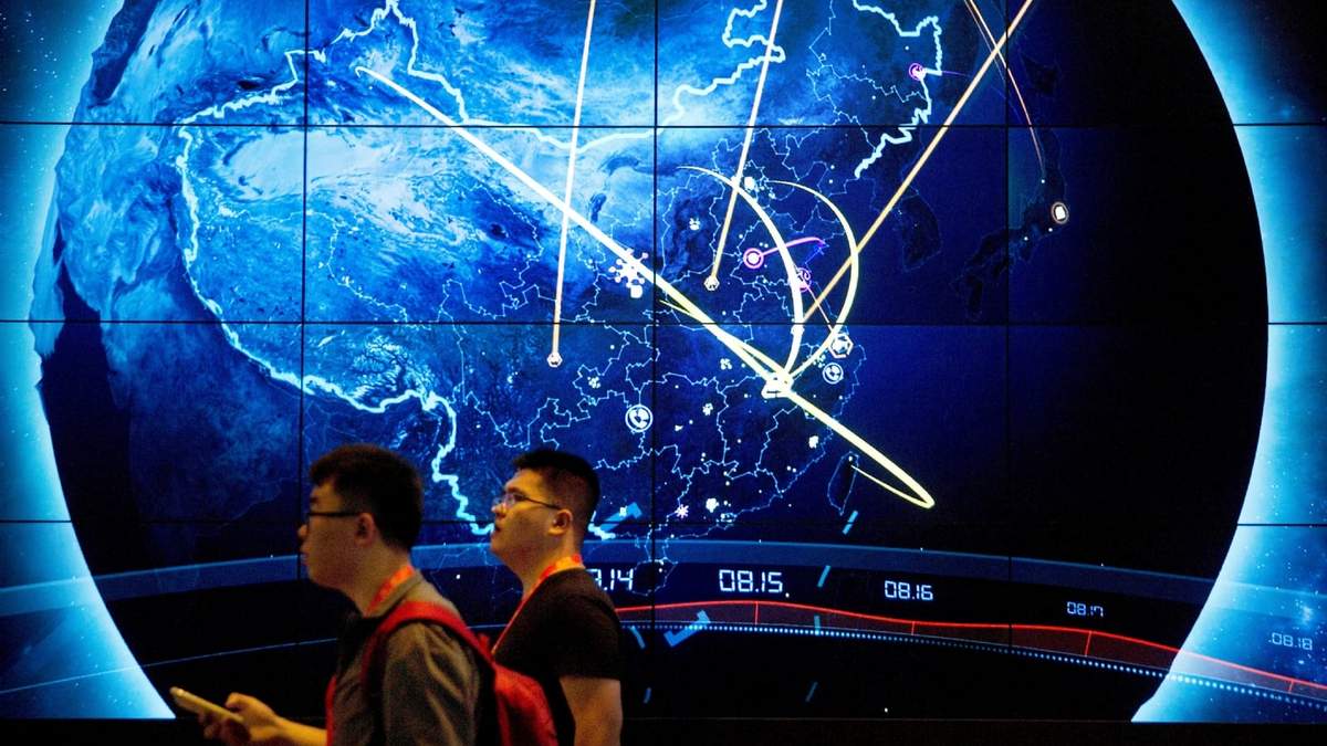 Dos asistentes pasan ante una pantalla que muestra ciberataques recientes en China, en la Conferencia China de Seguridad de Internet en Beijing, el 12 de septiembre de 2017