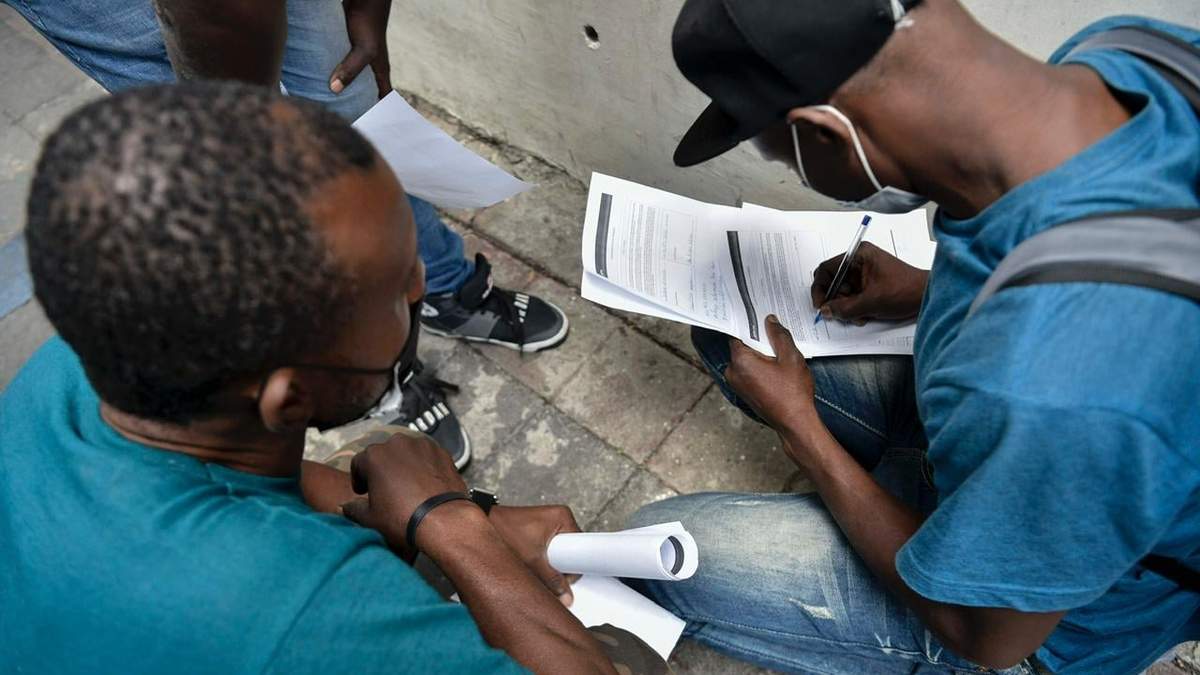 Migrantes haitianos llenan papeles para entrar a México