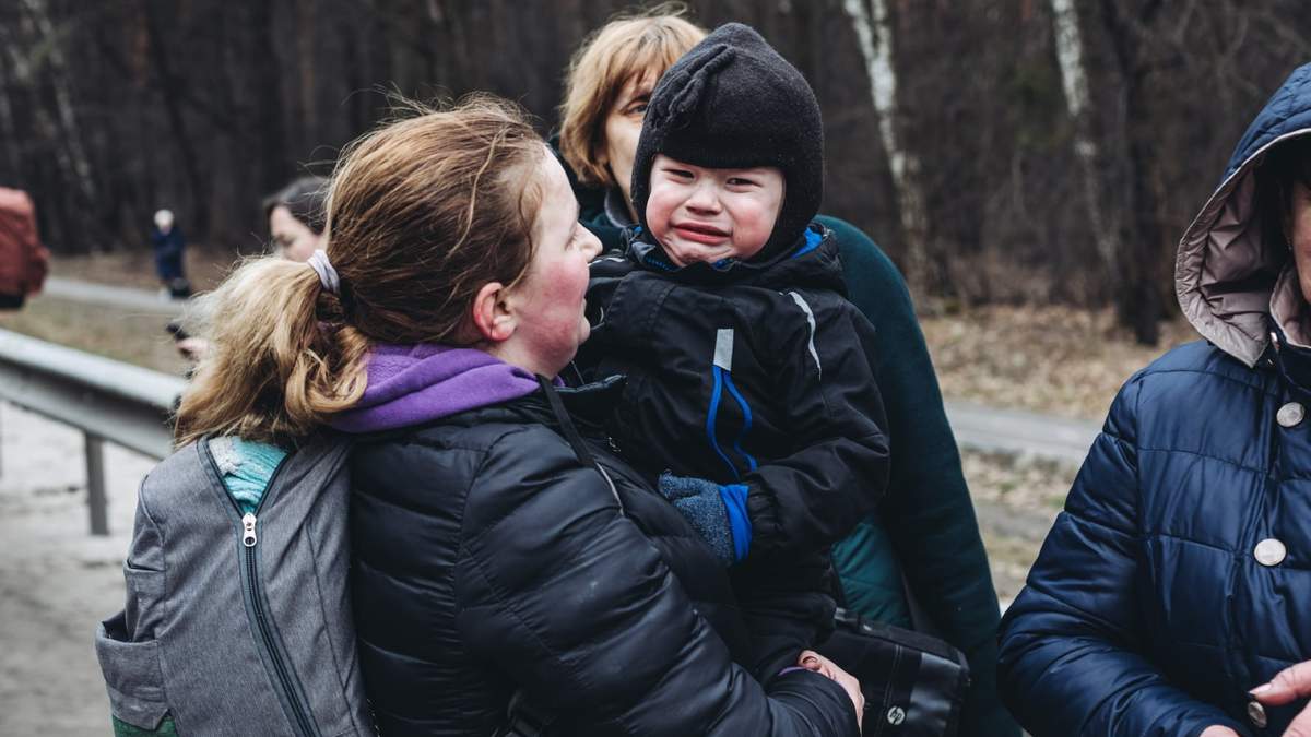 Un niño llora mientras espera para cruzar el río de Irpin, Ucrania