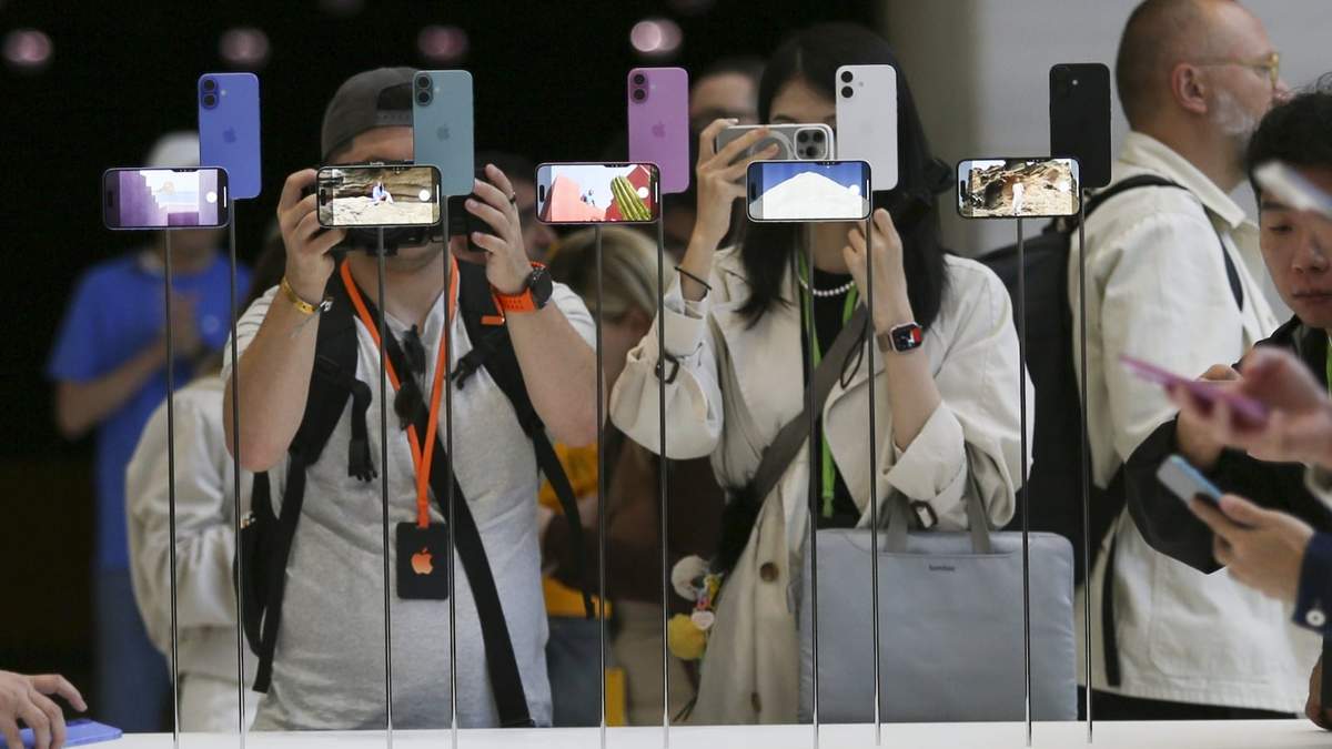 Dos asistentes observan de cerca el iPhone 16 de Apple durante un anuncio de nuevos productos