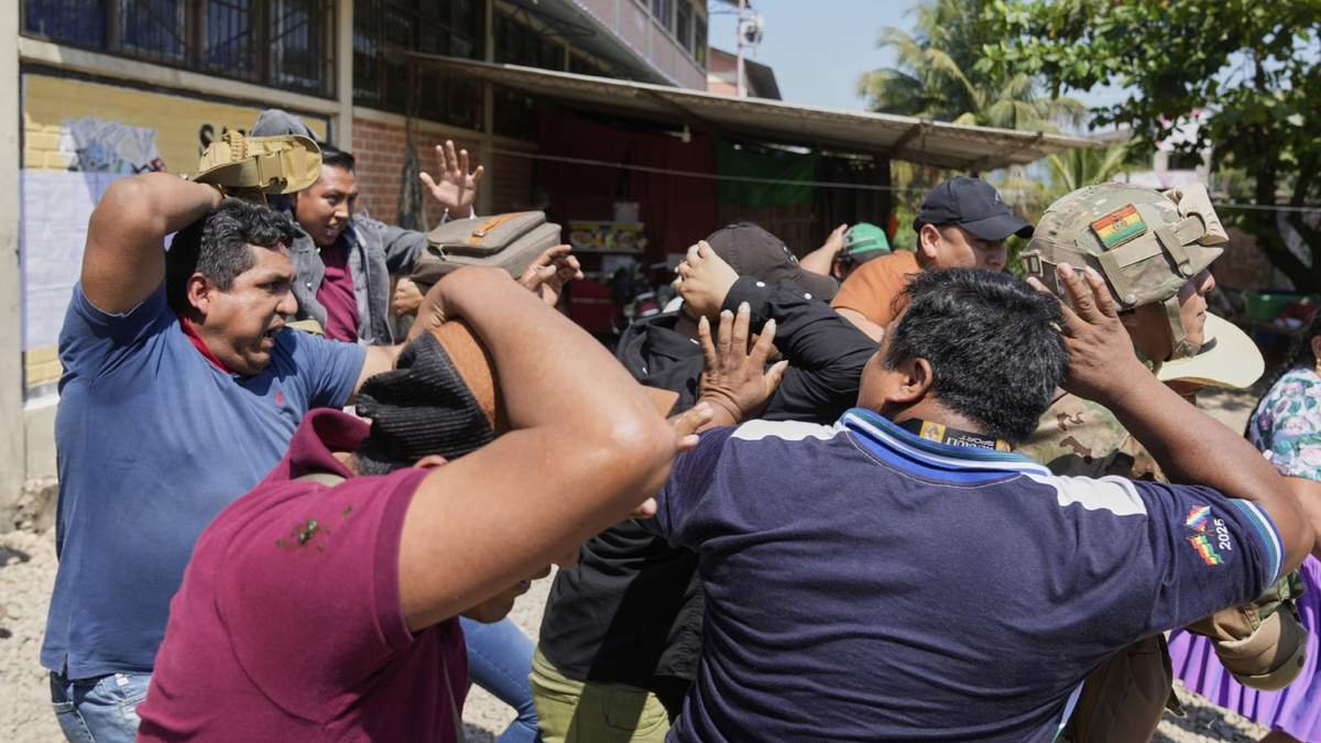 Guardias de seguridad rodean al candidato presidencial Andrónico Rodríguez a su salida de un colegio electoral tras votar, mientras sus opositores lanzan piedras