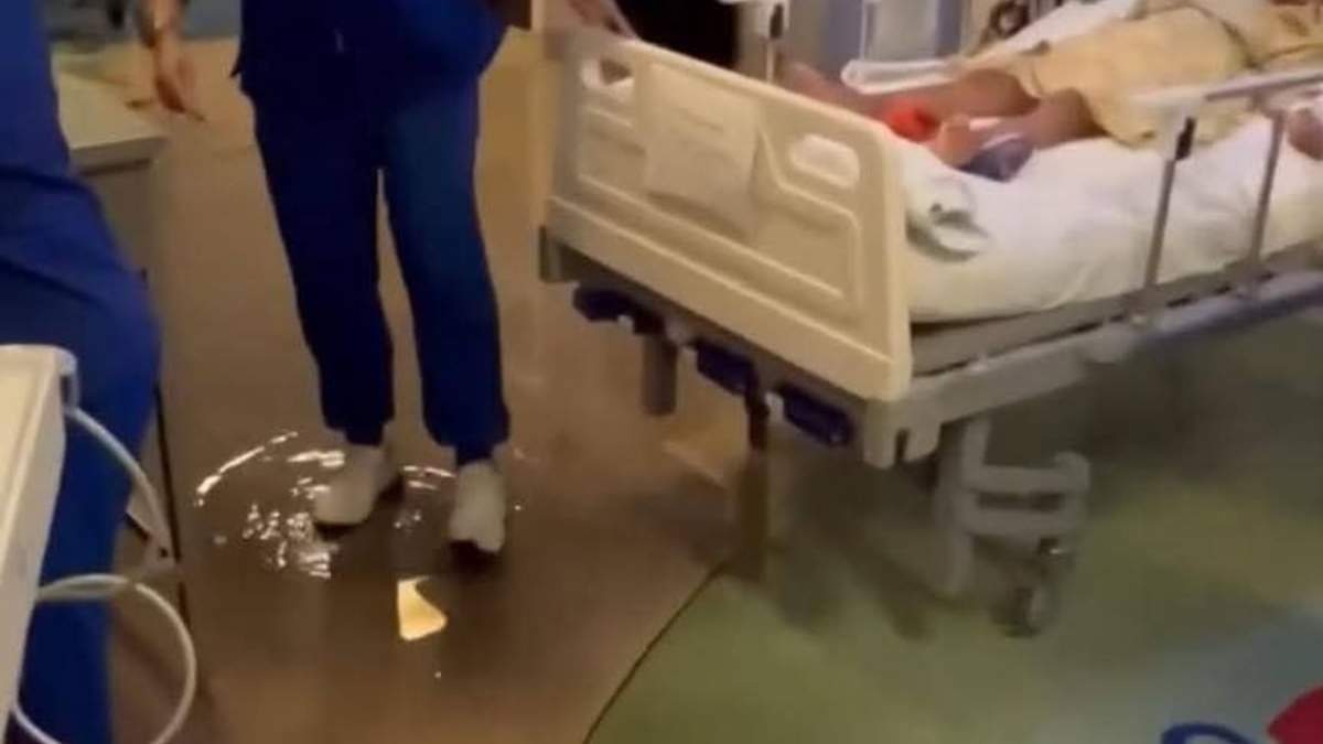 Una enfermera pasa sobre un chargo de aguas negras para mover a un paciente