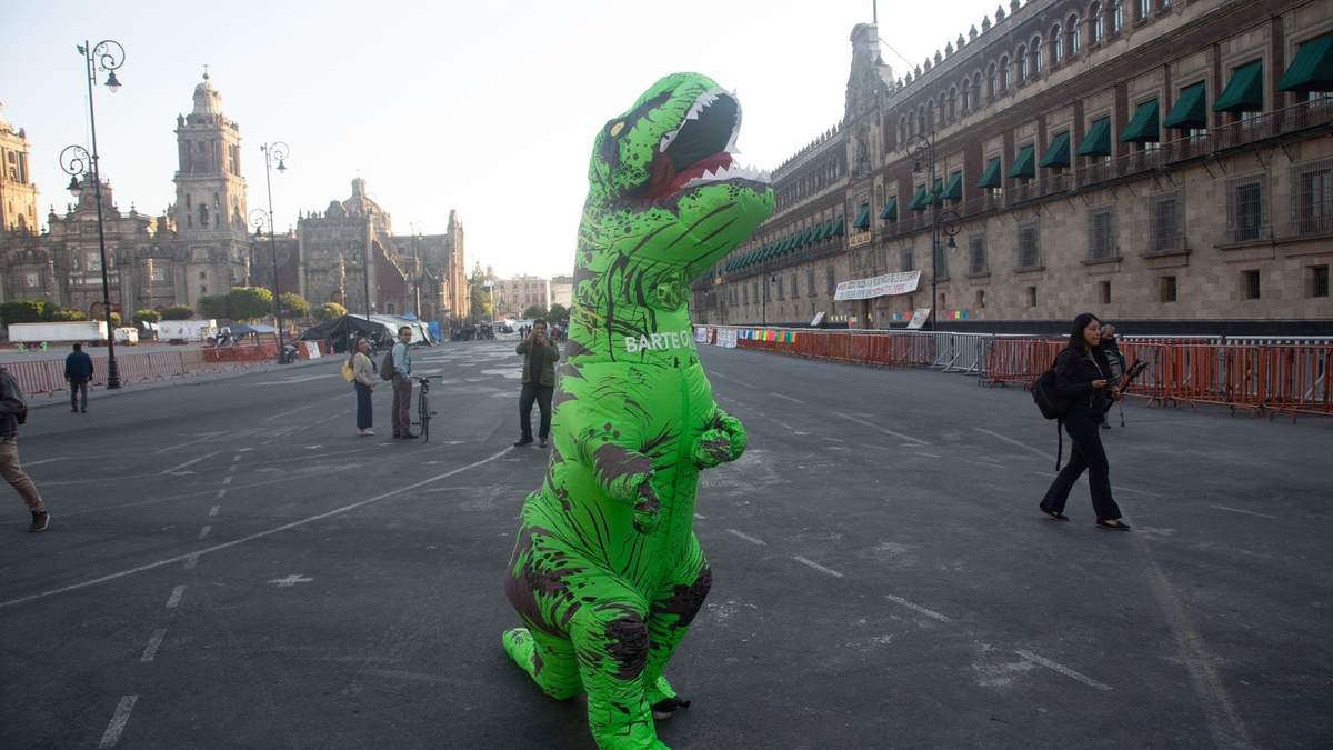 Manifestante portando botarga de dinosaurio en protesta por el Plan B, afuera de Palacio Nacional