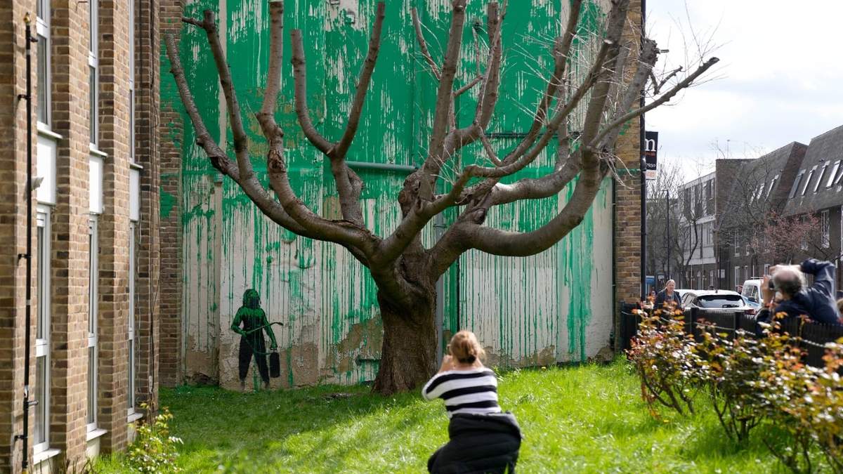 Personas miran un nuevo mural de Banksy en una pared en Londres