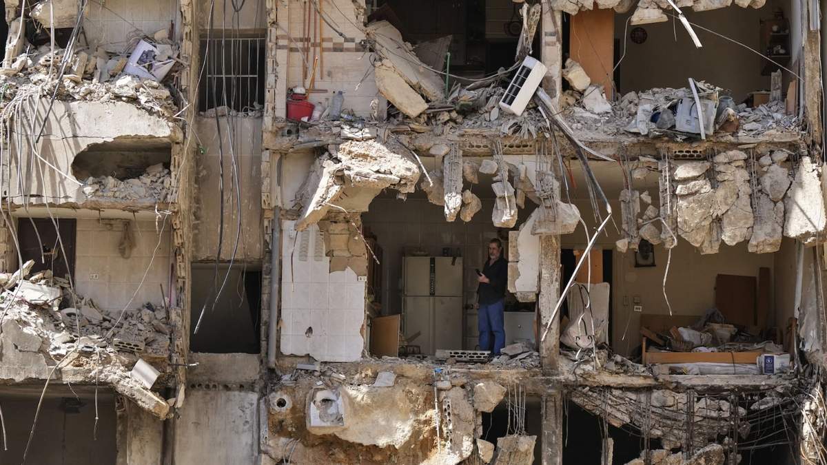 Un hombre observa a los rescatistas mientras revisan entre los escombros en busca de personas desaparecidas tras el ataque israelí del viernes sobre los suburbios del sur de Beirut