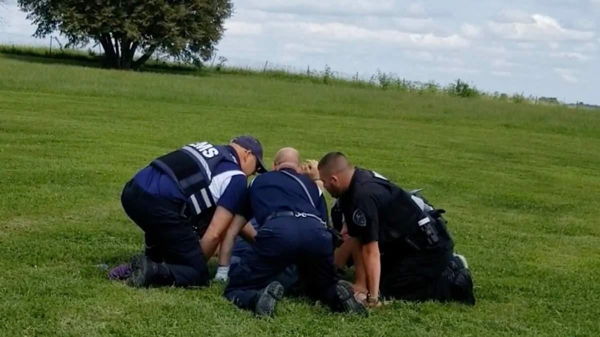Policía y personal médico de emergencias sujetan a Taylor Ware en un sitio para descansar a un costado de una carretera, en 2019
