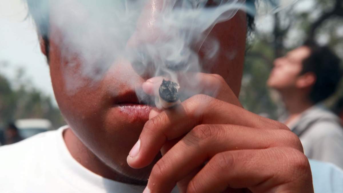 Joven fuma un cigarro de marihuana durante marcha por la legalización del consumo recreativo de esa planta en la CDMX