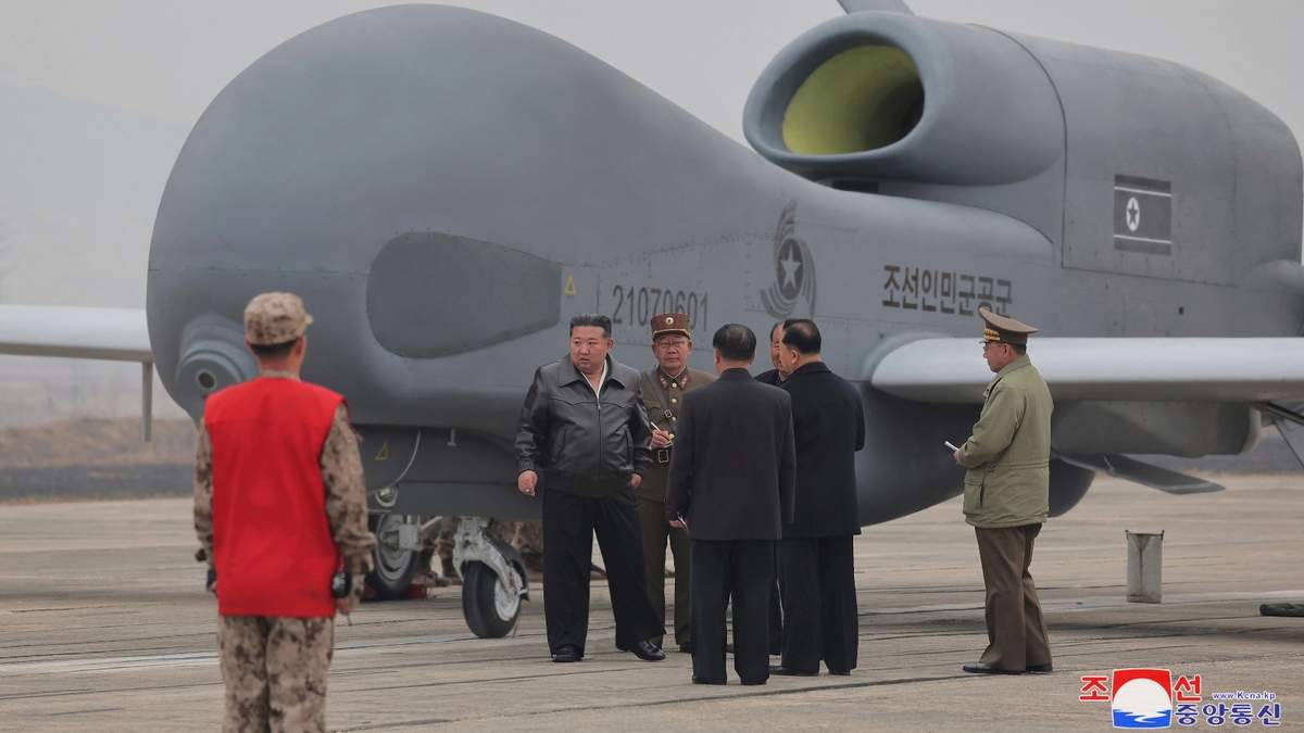 Kim Jong Un (izquierda) se encuentra junto a lo que parece ser un dron de reconocimiento de gran tamaño en un sitio no revelado en Corea del Norte