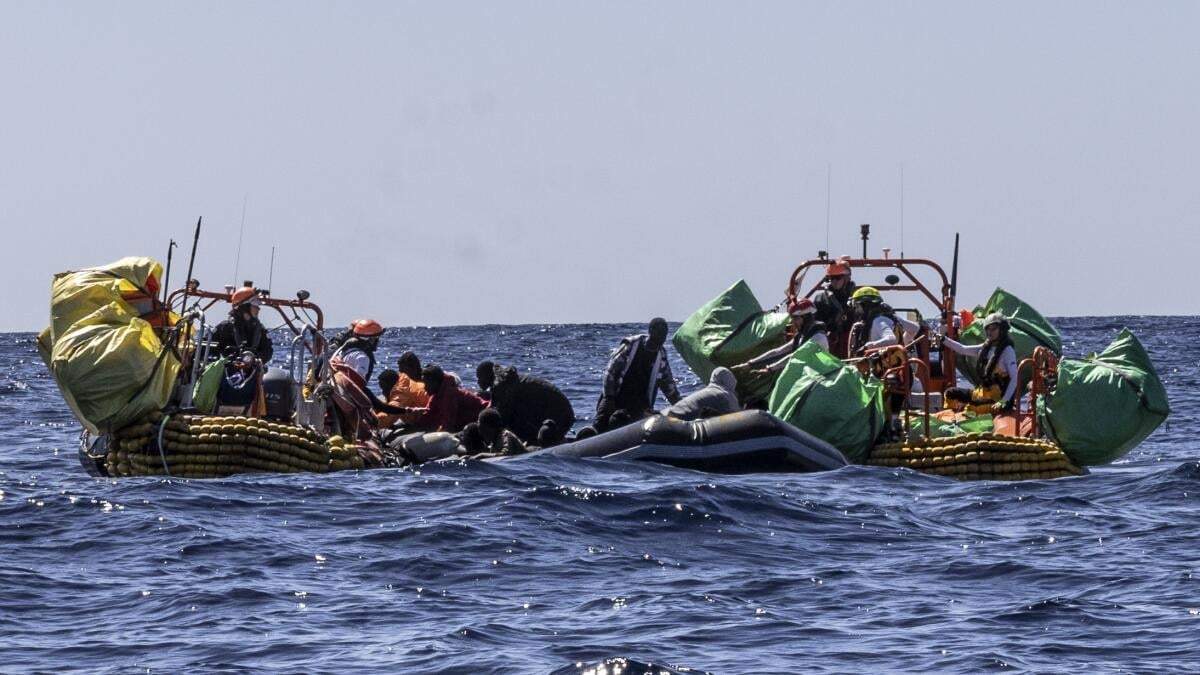 Personal de rescate del barco humanitario Ocean Viking de SOS Mediterranee ayuda a migrantes a evacuar un bote de goma parcialmente desinflado en el Mar Mediterráneo