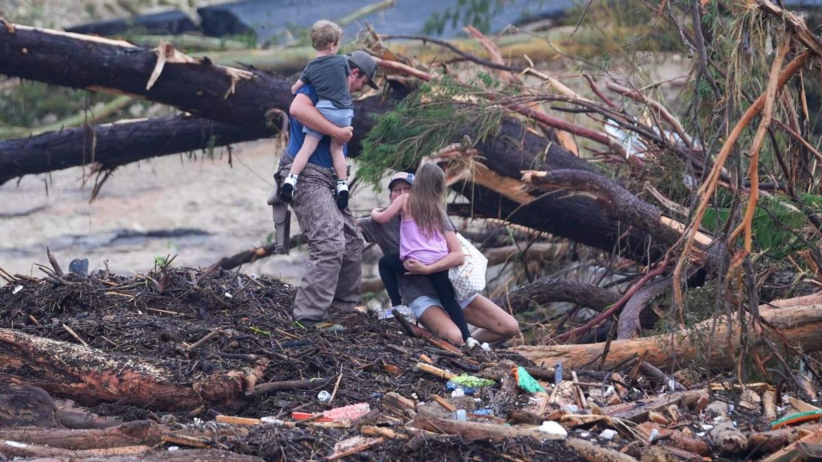Una mujer se cae mientras camina entre escombros en un puente sobre el río Guadalupe luego de que una inundación repentina azotó la zona de Ingram, en Texas