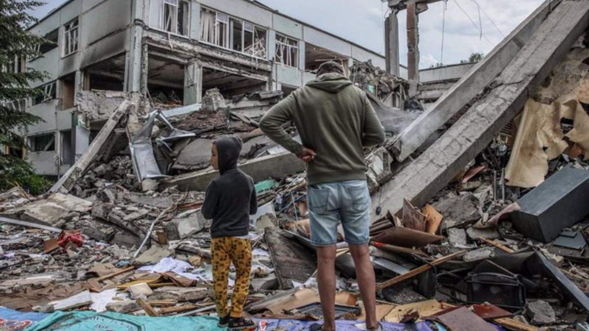 Un padre y su hijo en medio de los escombros de un colegio atacado por las fuerzas rusas, en Járkov
