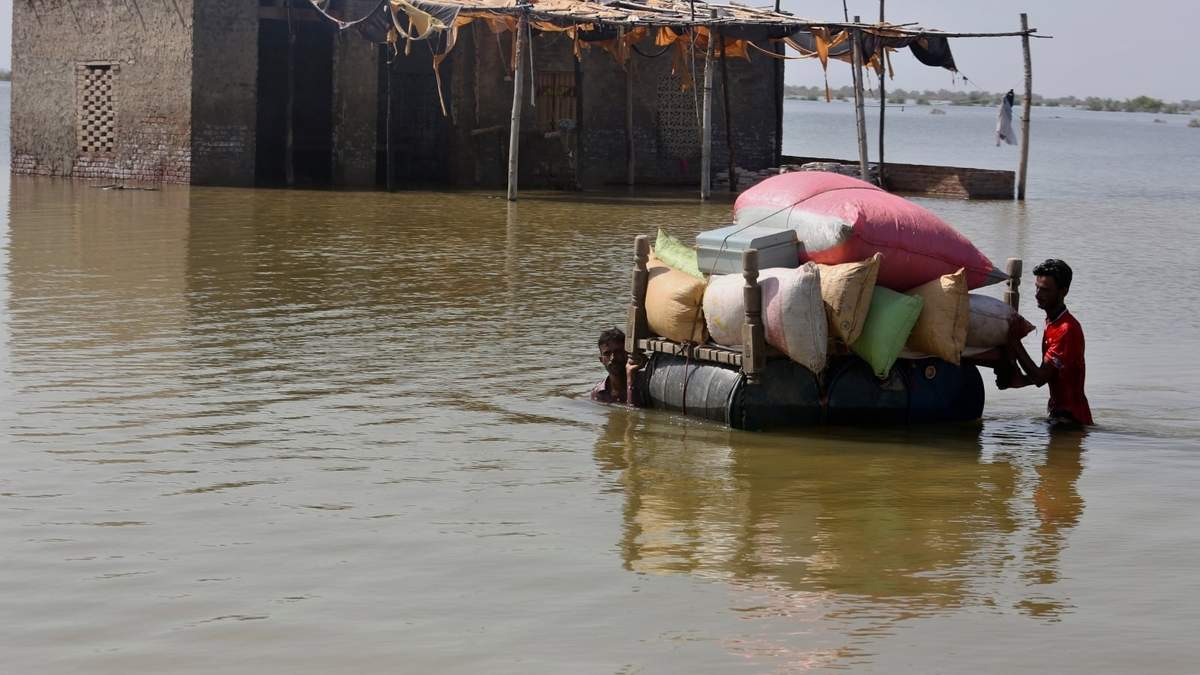 Personas afectadas por las inundaciones usan un catre para rescatar sus pertenencias en el distrito de Qambar Shahdadkot