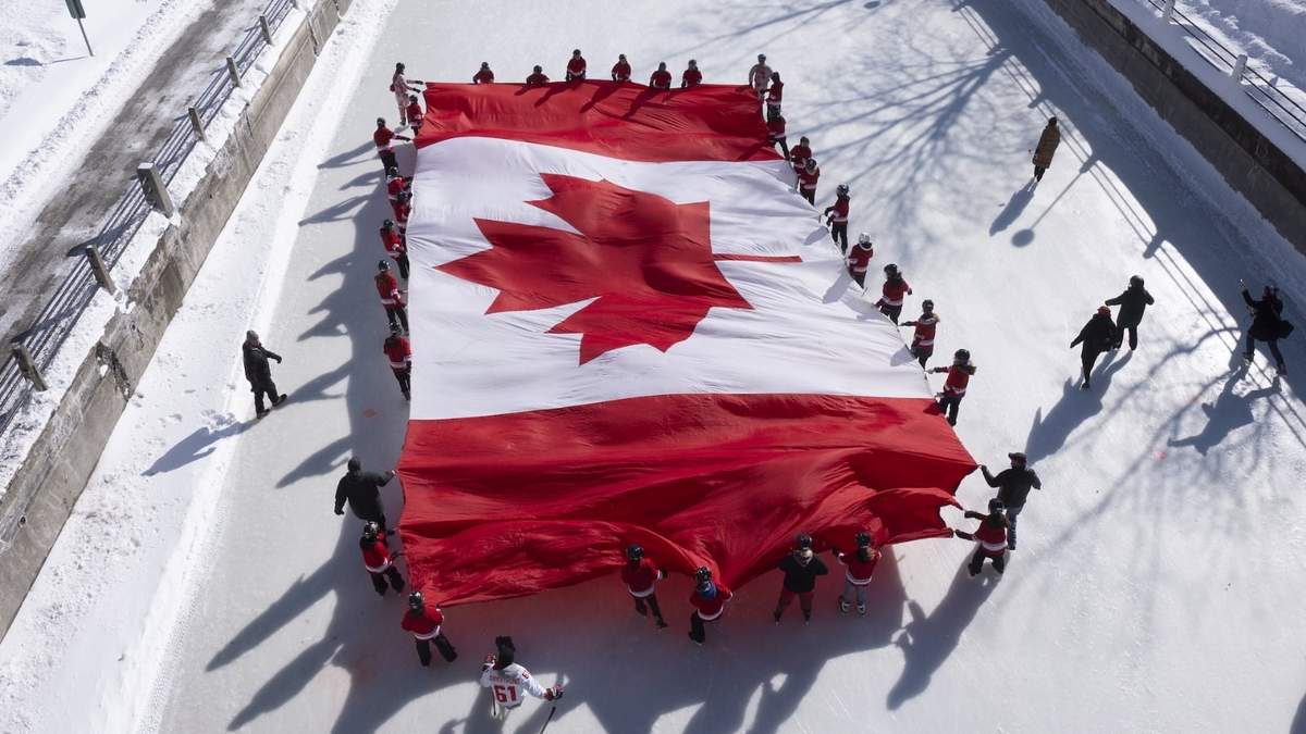 Jóvenes patinadores extienden una bandera canadiense en el Canal Rideau como parte de la conmemoración del 60 aniversario de la bandera nacional