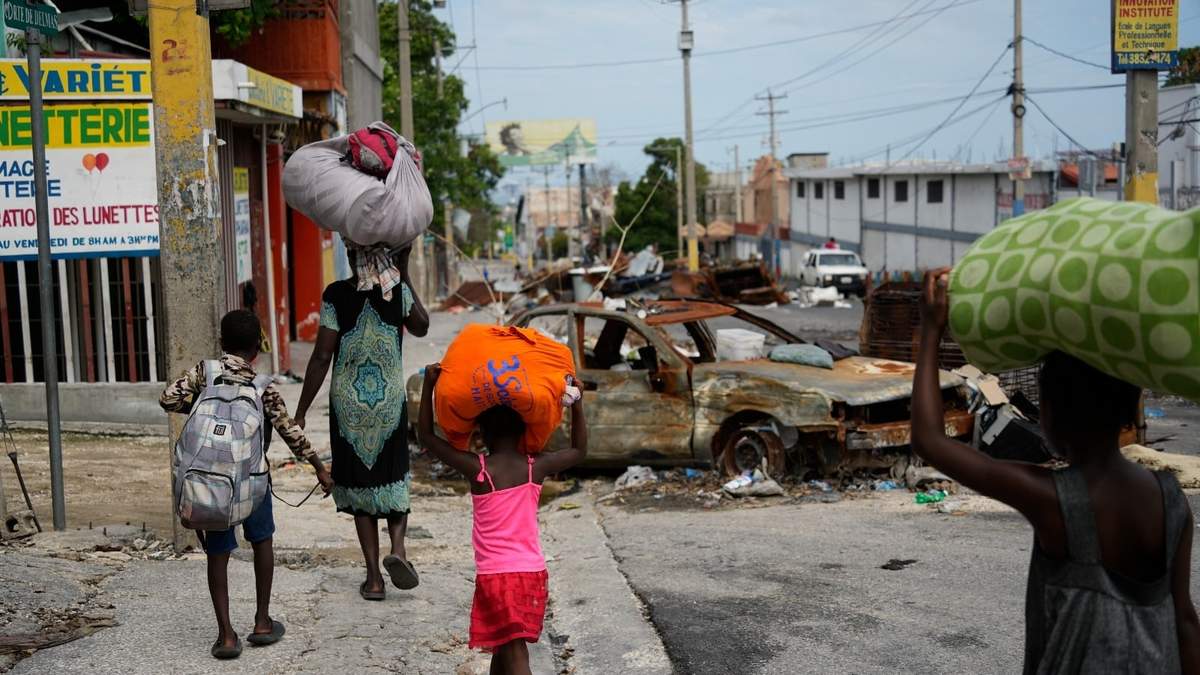 Residentes caminan por un camino bloqueado al evacuar el vecindario Delmas 22 para huir de la violencia de las pandillas en Puerto Príncipe
