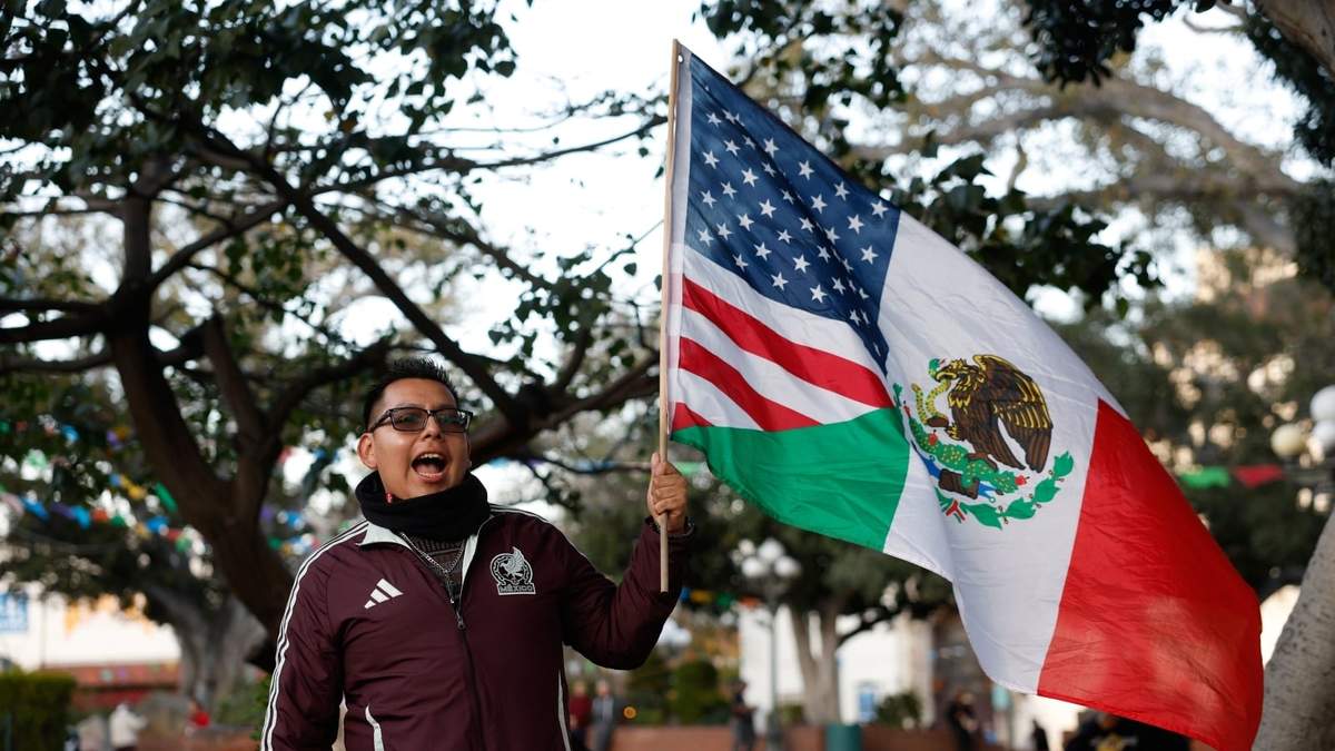 Un hombre ondea una bandera compuesta con los lábaros de Estados Unidos y México durante una protesta en Minnesota